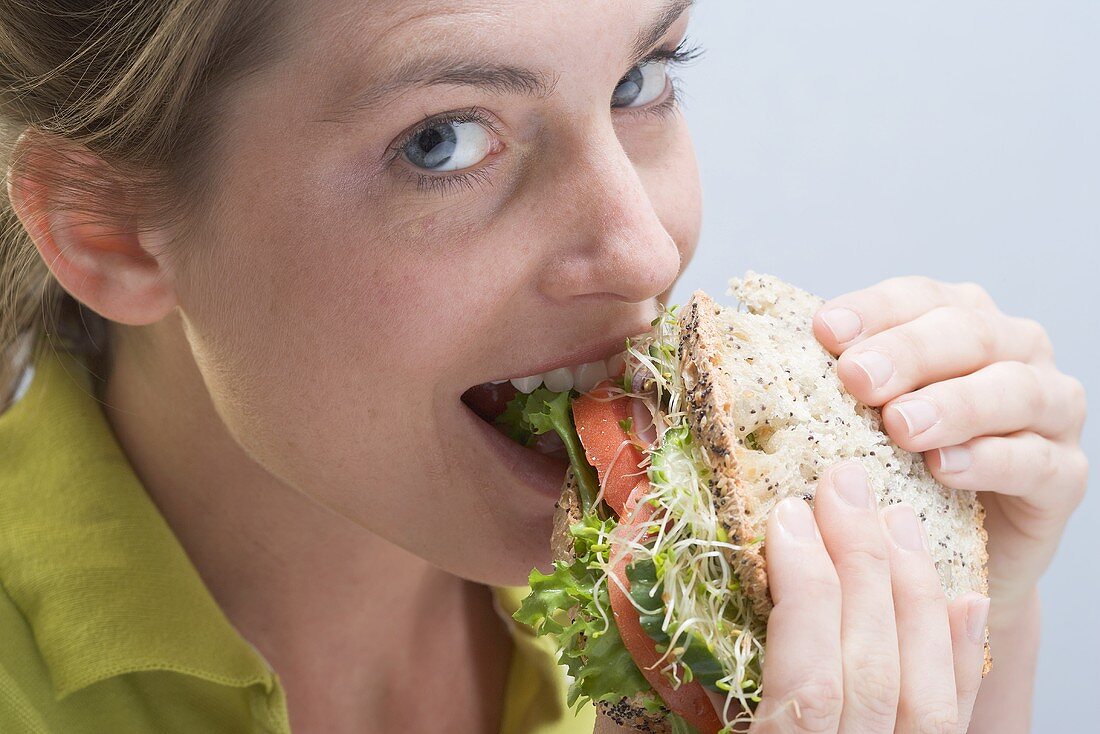 Frau beisst genussvoll in ein Sandwich