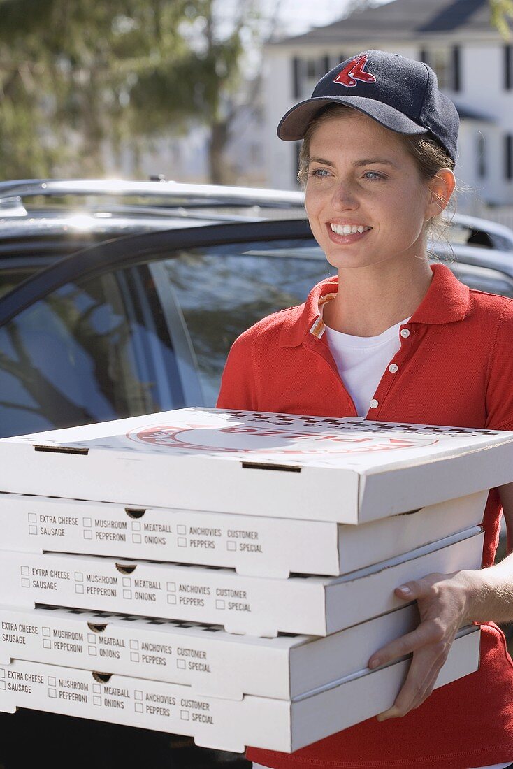 Lächelnde Frau bringt fünf Schachtel mit frischer Pizza