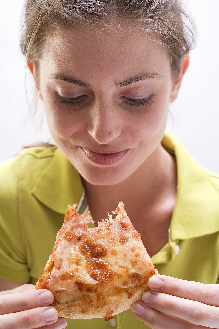 Junge Frau mit abgebissenem Stück Pizza Margherita