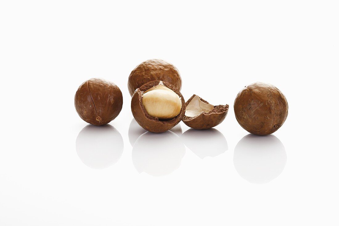 Several macadamia nuts, one cracked open