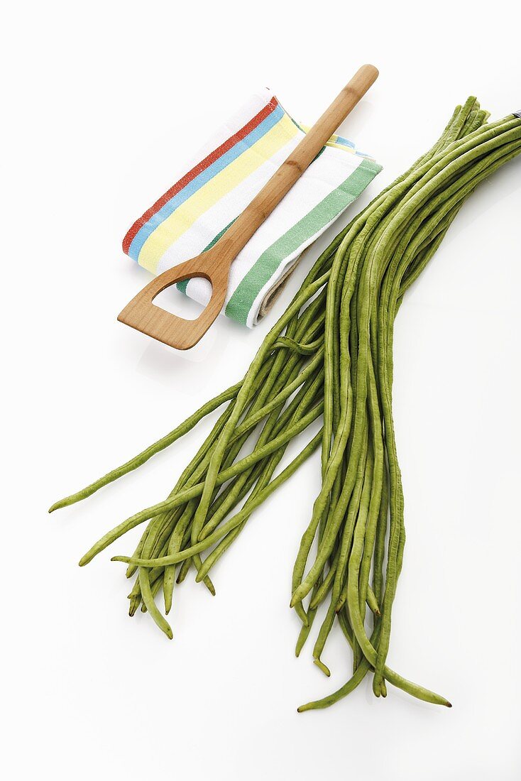 Yardlong beans, tea towel and wooden spoon