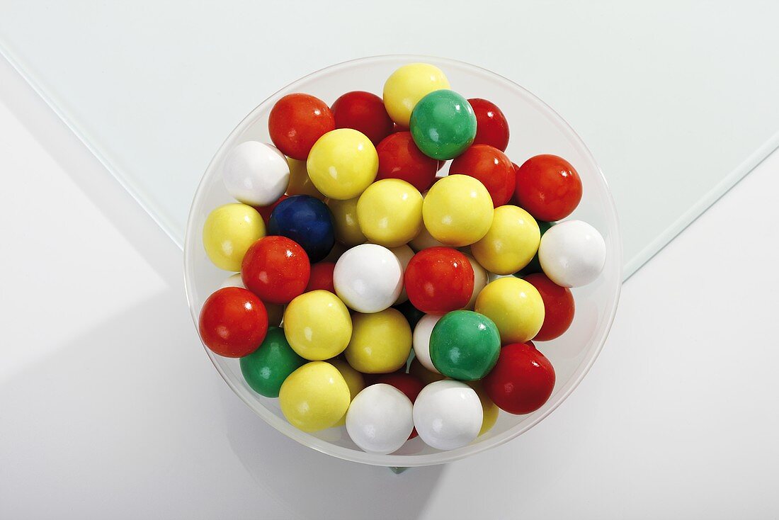 Coloured bubble gum balls in a bowl (overhead view)