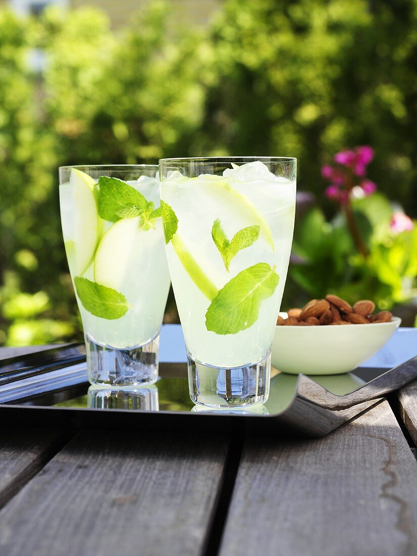 Two glasses of lemonade with fresh mint on table out of doors