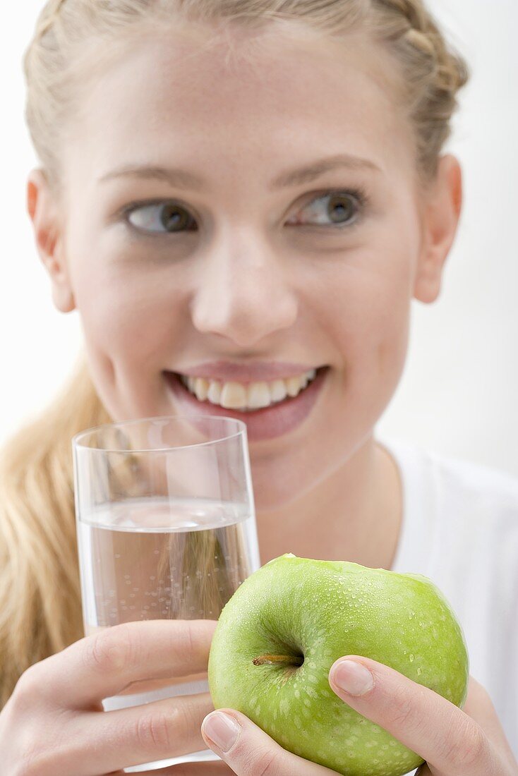 Frau hält Apfel und Glas Wasser