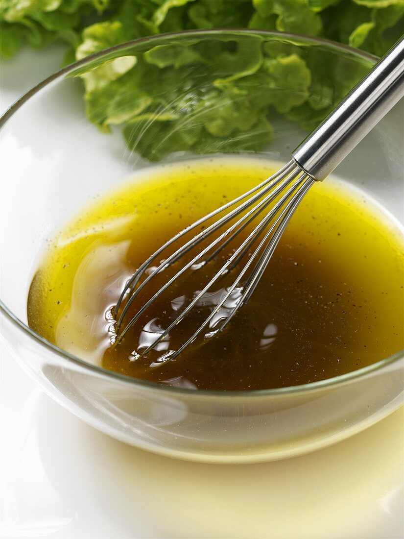 Salad dressing (vinaigrette) in glass dish with whisk