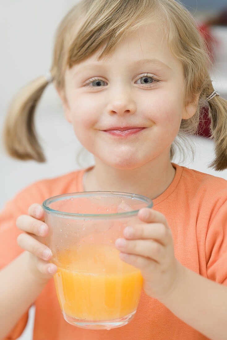 Kleines Mädchen trinkt Orangensaft