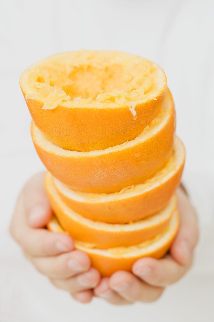 Hände halten ausgepresste Orangen