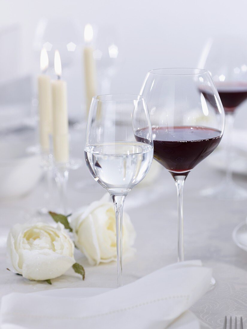 Glasses of red & white wine on table laid for special occasion