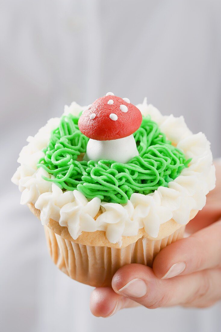 Hand holding cupcake with marzipan fly agaric