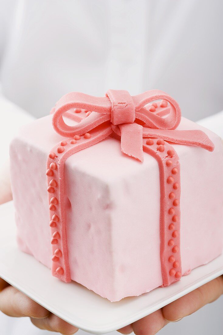 Hands holding cake with marzipan ribbon