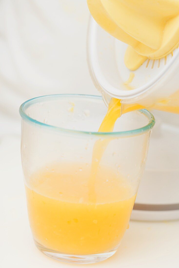 Frisch gepressten Orangensaft in Glas gießen