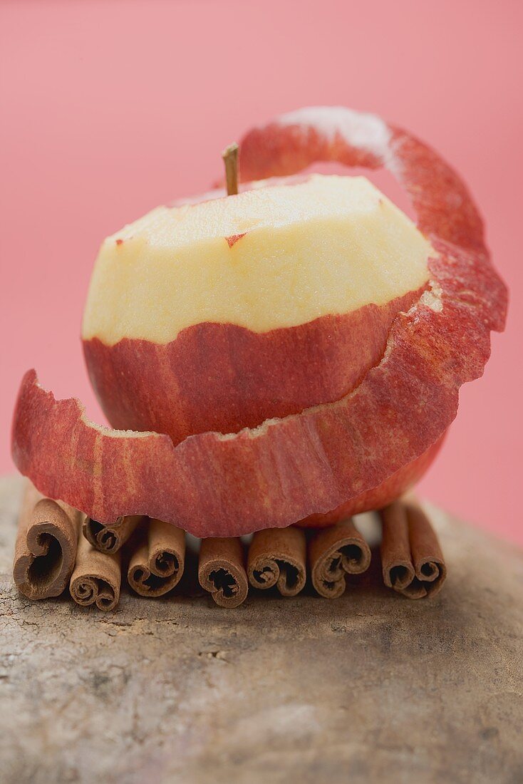 Apple, partly peeled, on cinnamon sticks