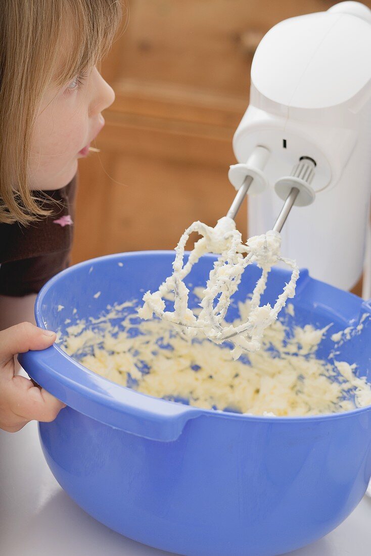 Kleines Mädchen rührt Butter mit Mixer