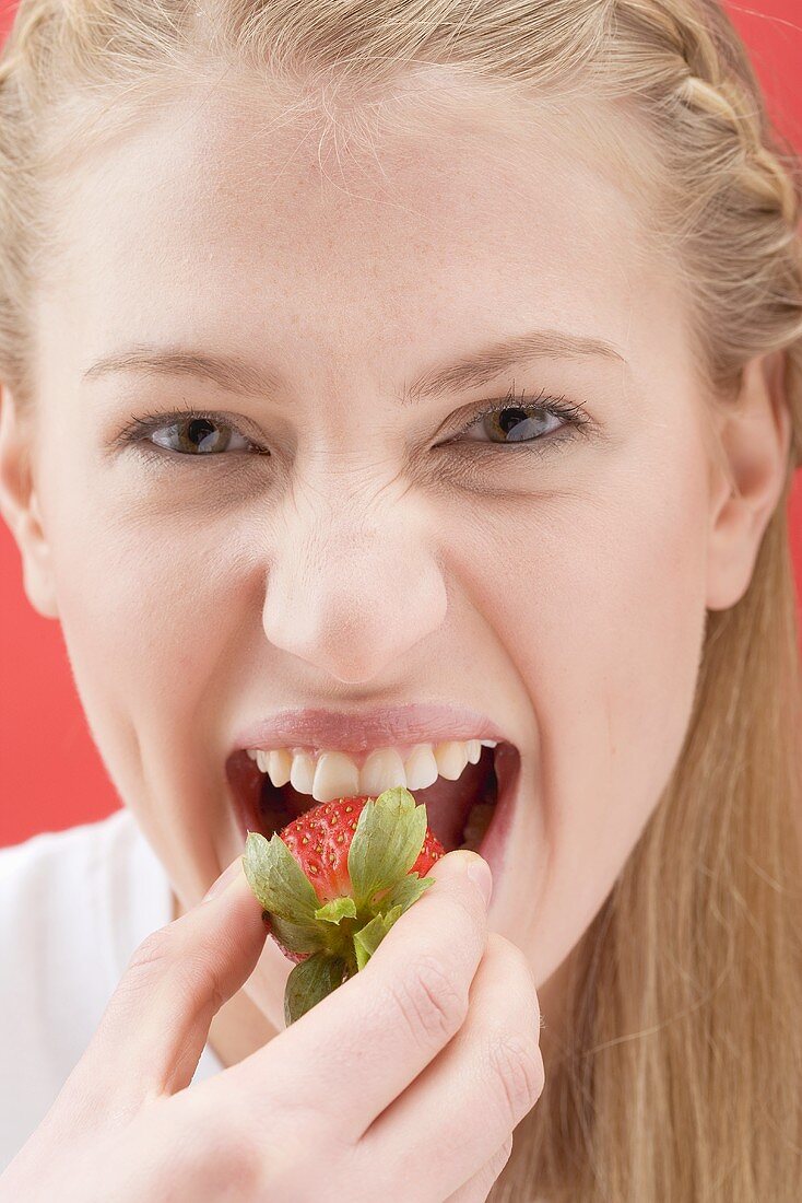 Frau beisst in Erdbeere