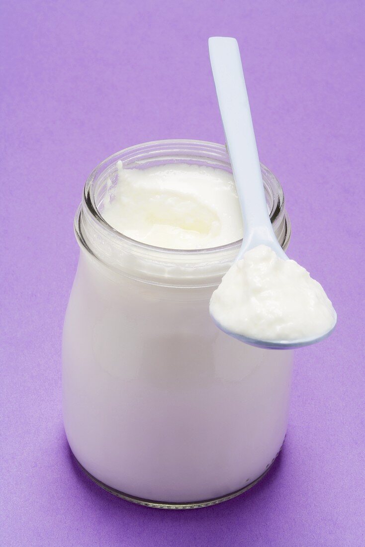 Yoghurt in jar and on plastic spoon