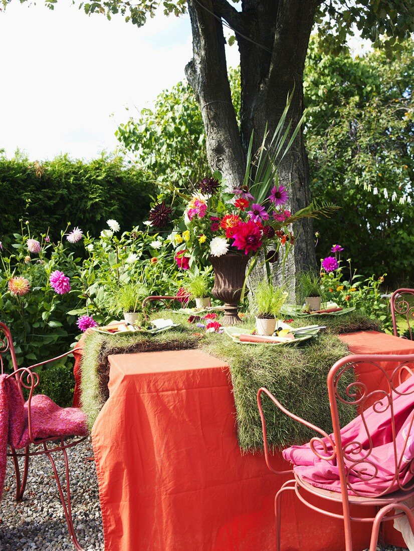 Laid table decorated with flowers and turf out of doors
