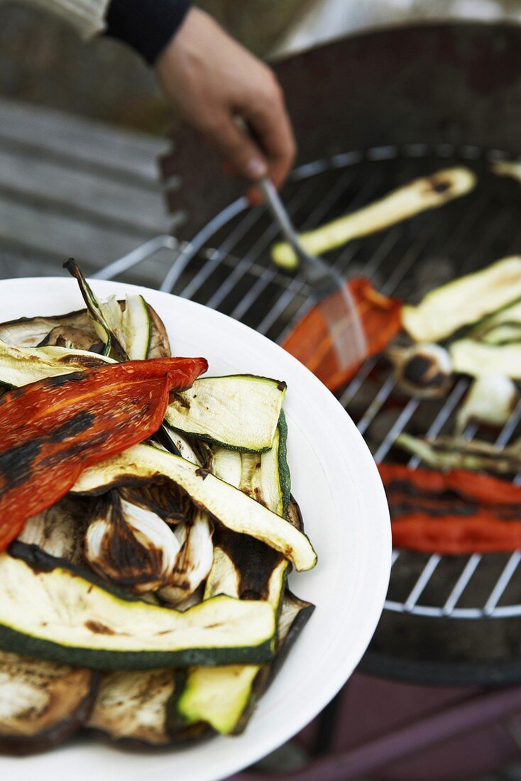 Grilled vegetables on a plate and on a barbecue