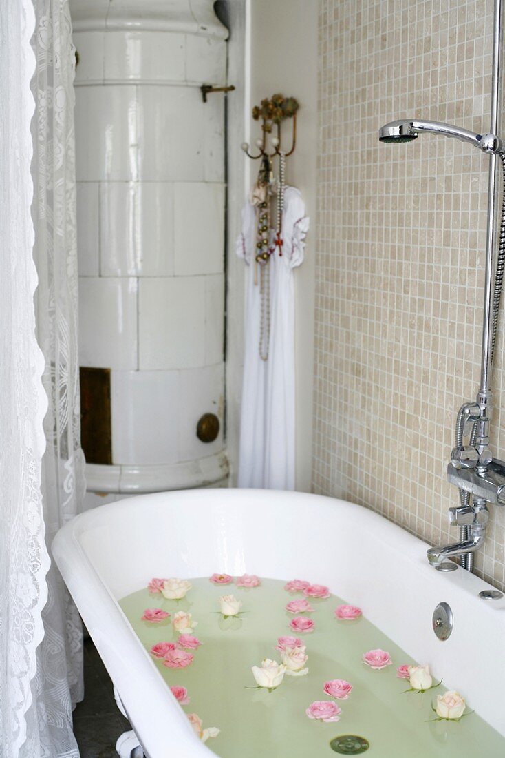 Nostalgische Badewanne mit im Badewasser schwimmenden Rosenblüten