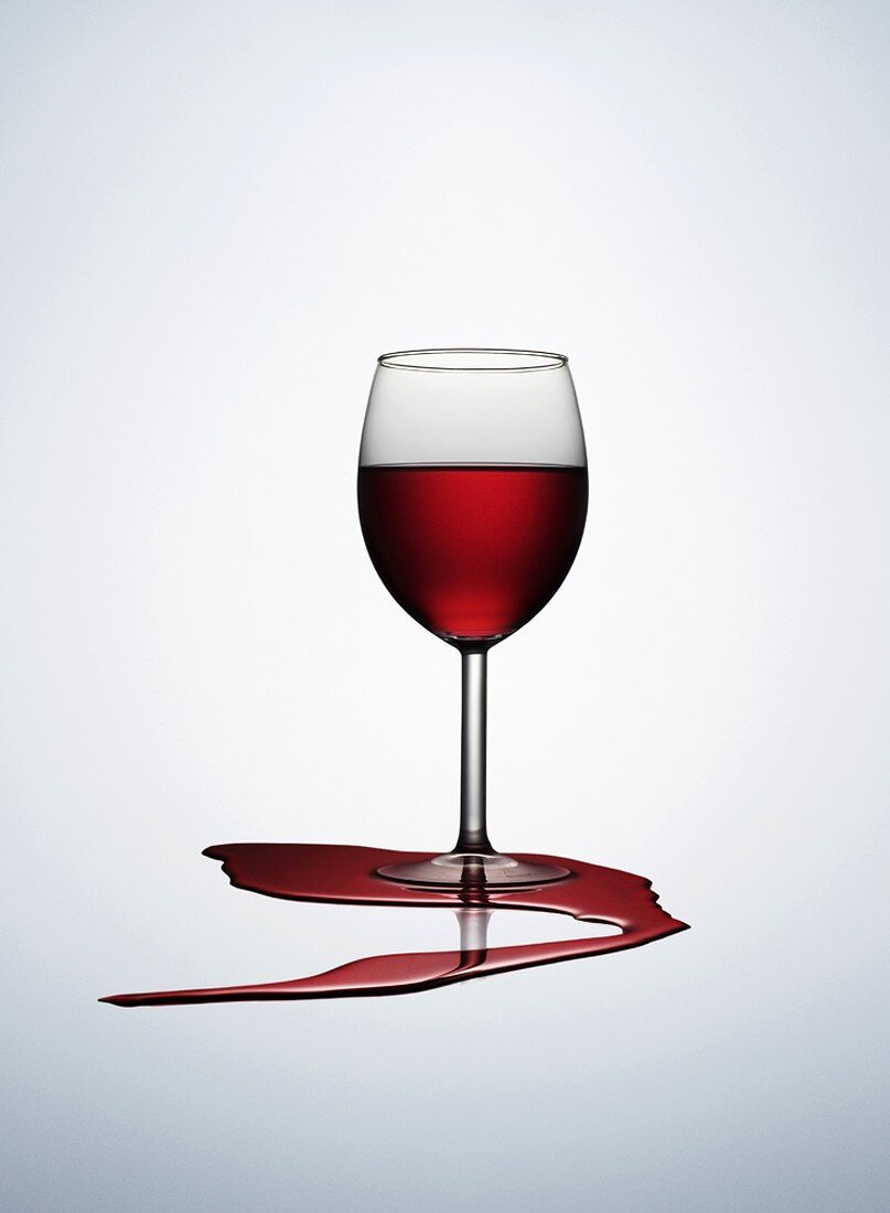 A glass of red wine with spilt wine