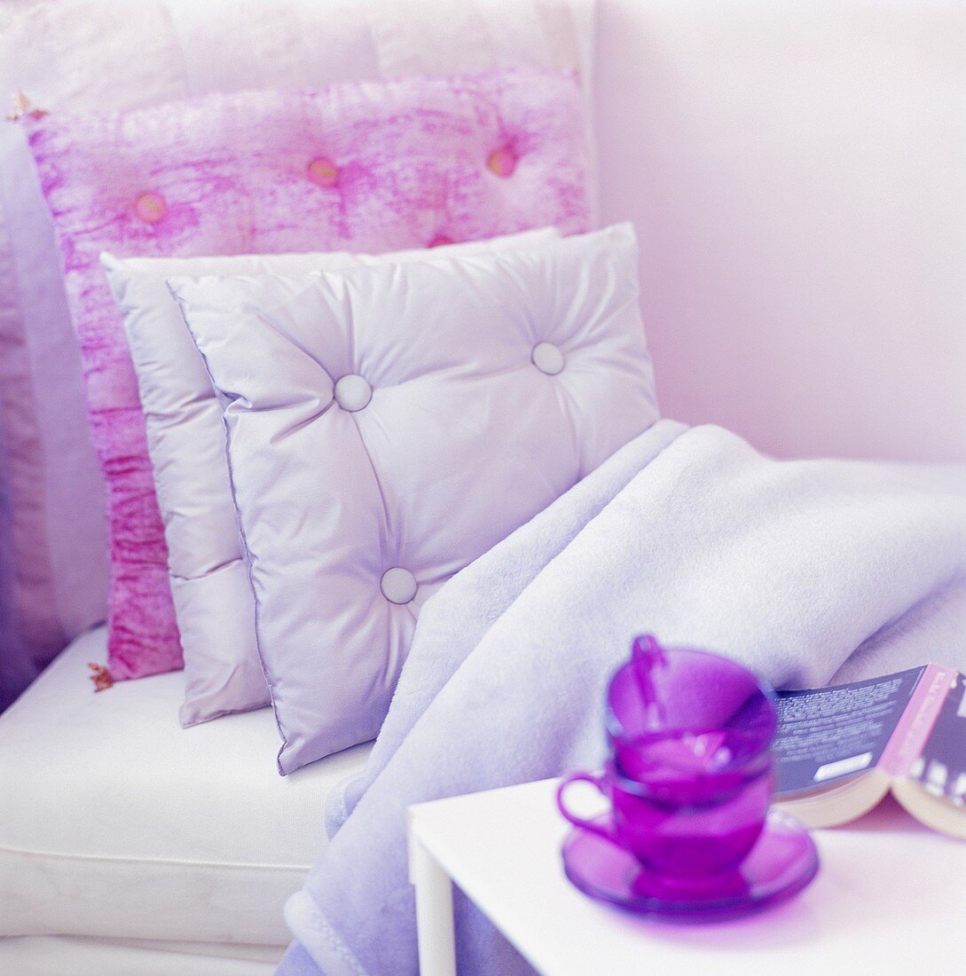 Bed with cushions & throw, cups, saucers & book on side table