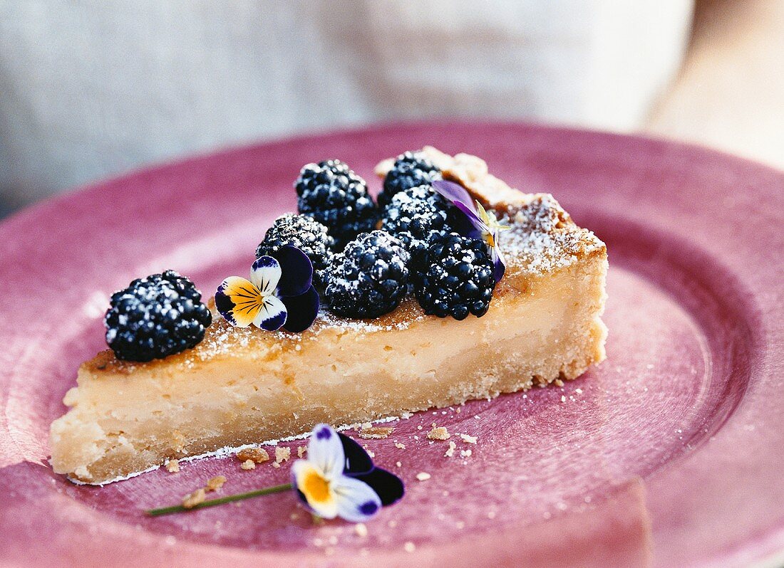 A piece of blackberry tart with pansies