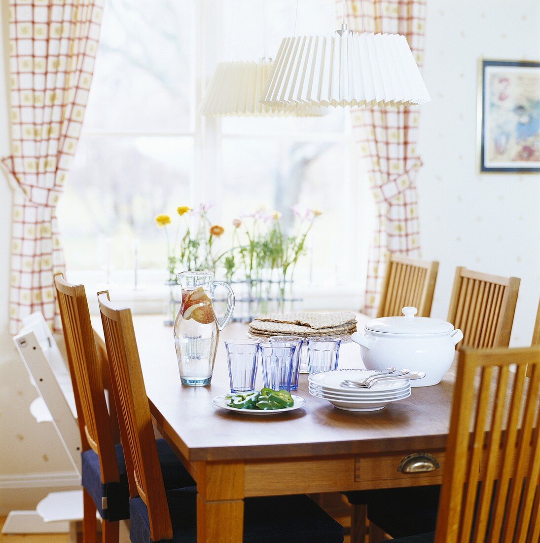 Dining table with plates and glasses by window