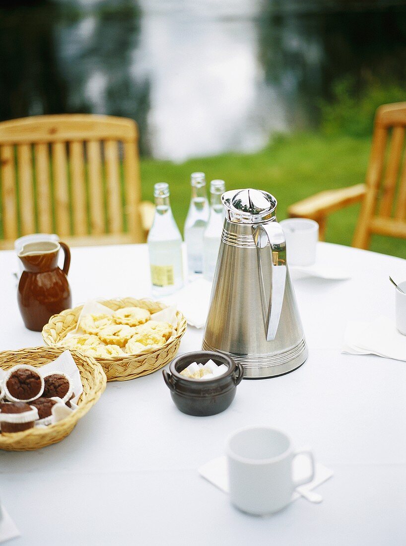Laid table with Thermos jug and small cakes out of doors