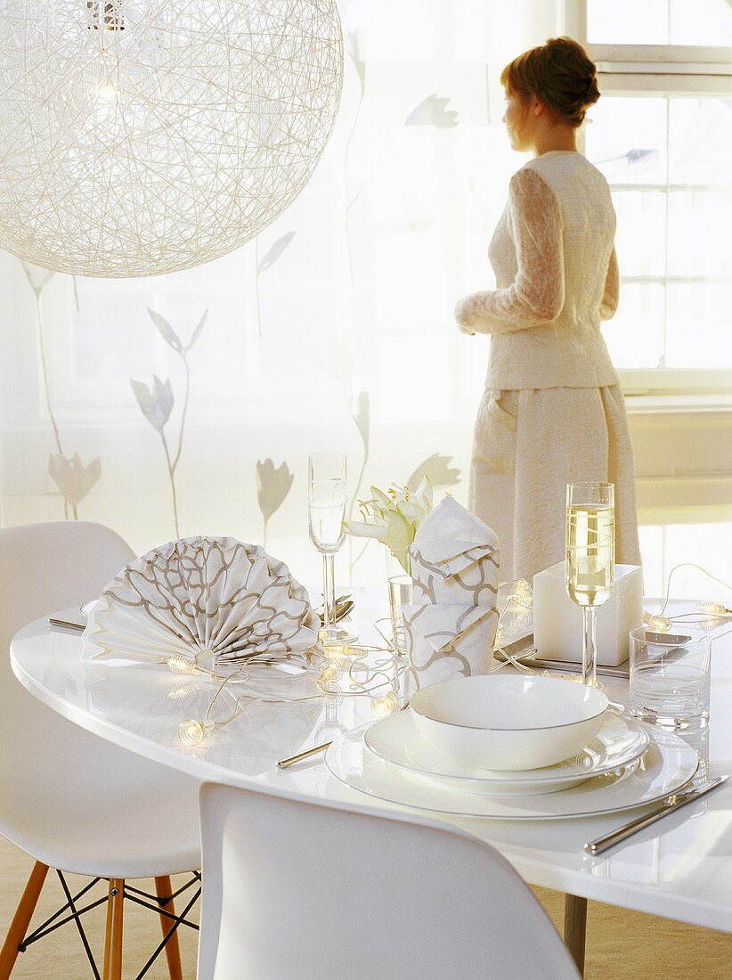 Woman dressed in white standing behind elegantly laid table