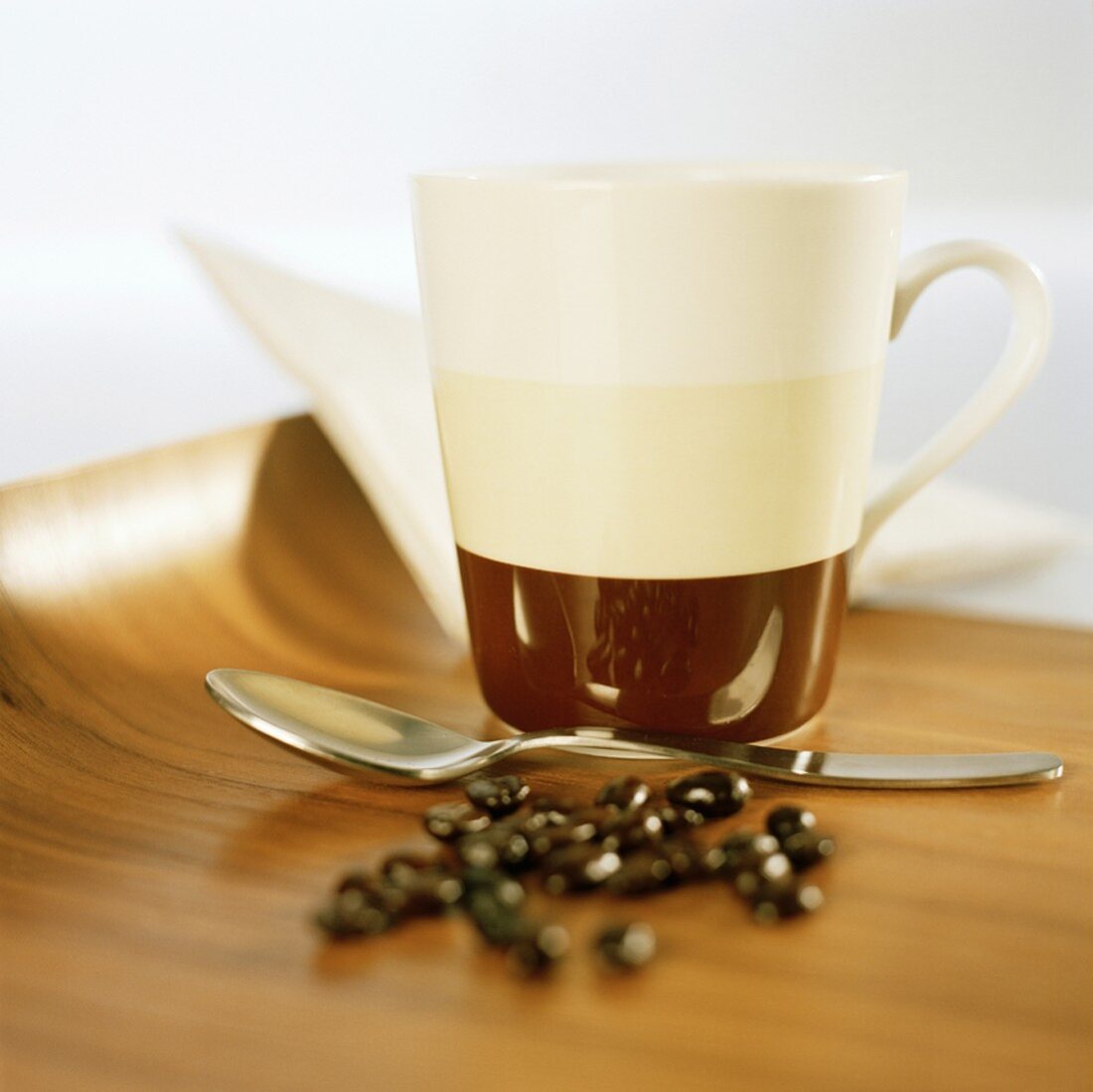 A coffee mug, spoon and coffee beans