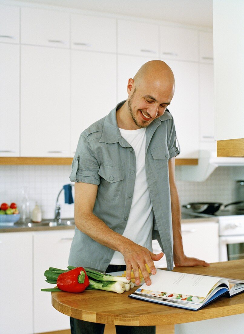 Man leafing through cookery book in kitchen