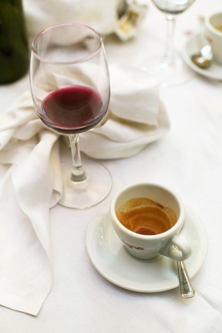 Leere Espressotasse und Rotweinglas