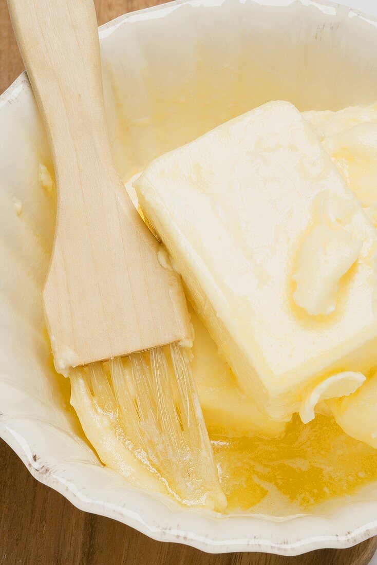 Melting butter with pastry brush in dish (close-up)