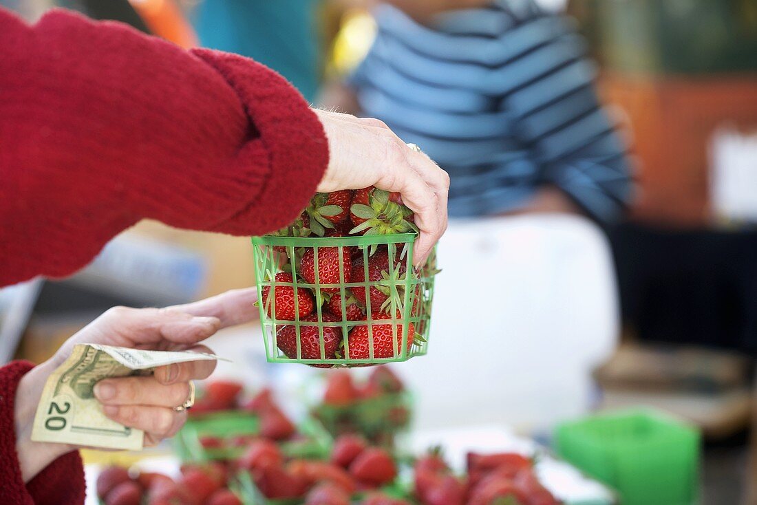 Frau kauft Erdbeeren am Markt