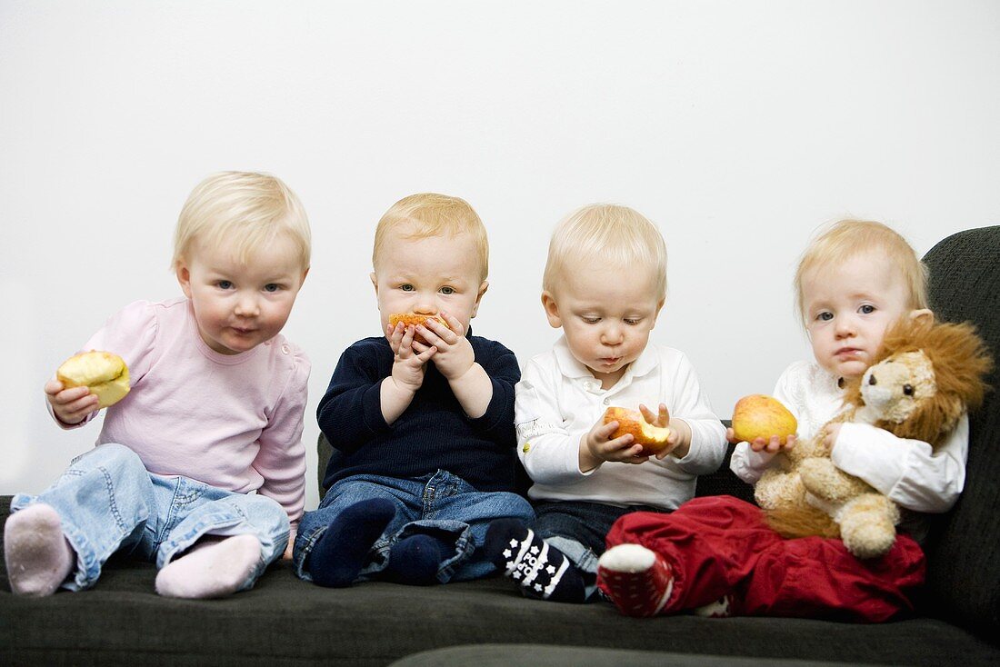 Vier Kleinkinder essen Äpfel