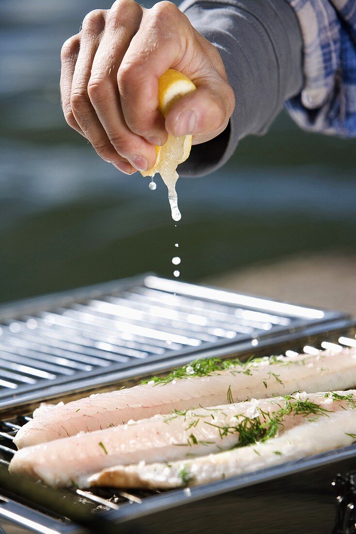Man sprinkling fish with lemon juice (Sweden)