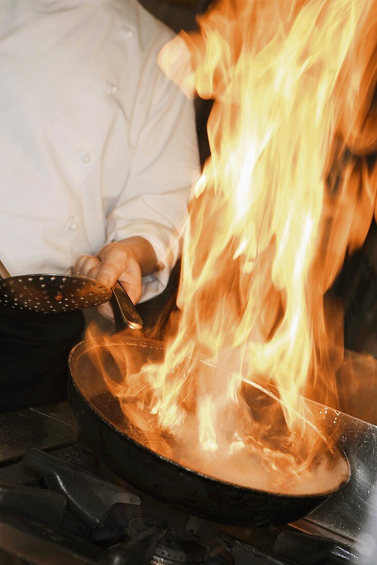 Chef flambéing a dish in a frying pan