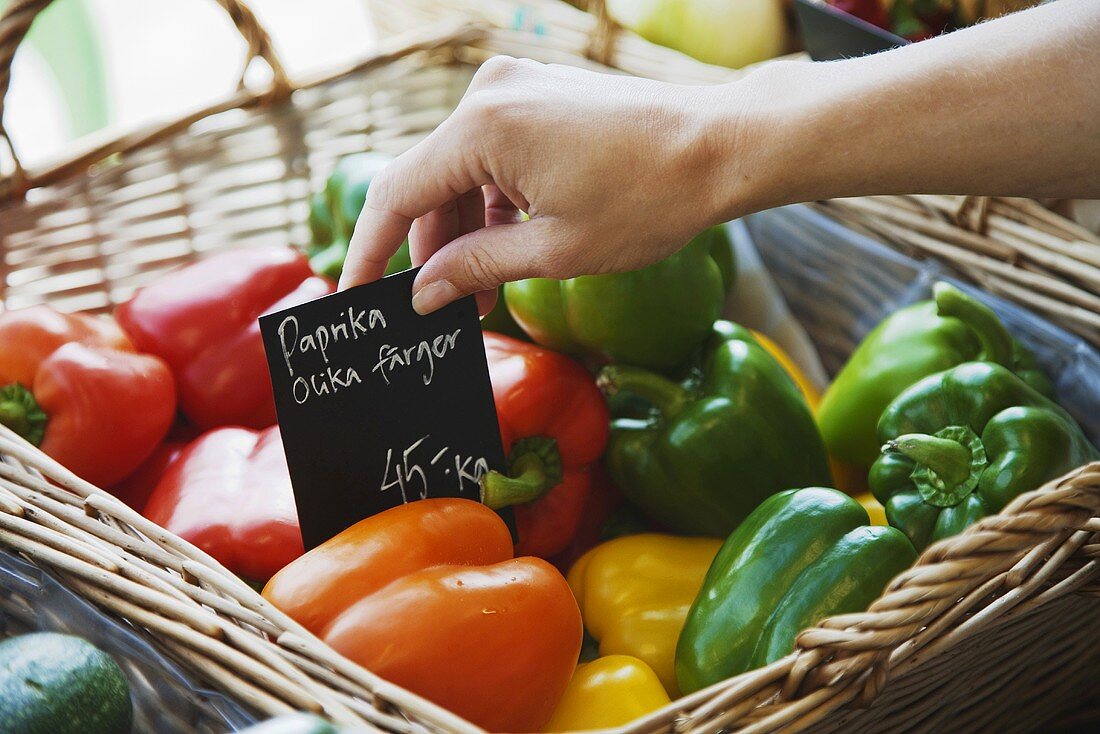 Hand putting sign among peppers in basket (Sweden)