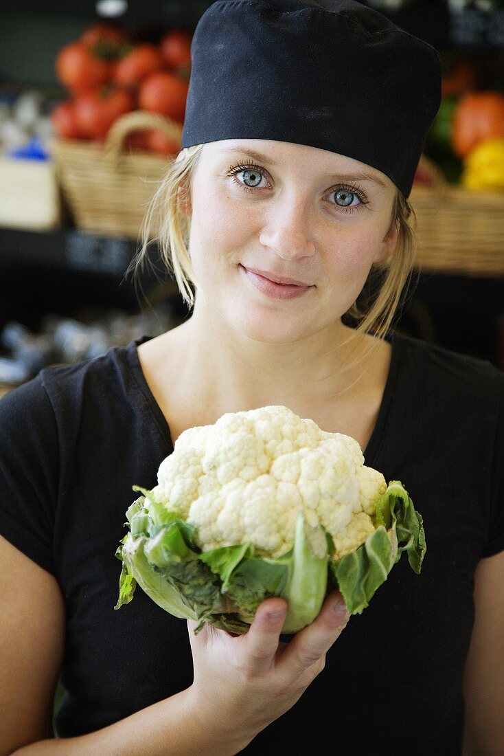 Angestellte im Supermarkt bietet Blumenkohl an