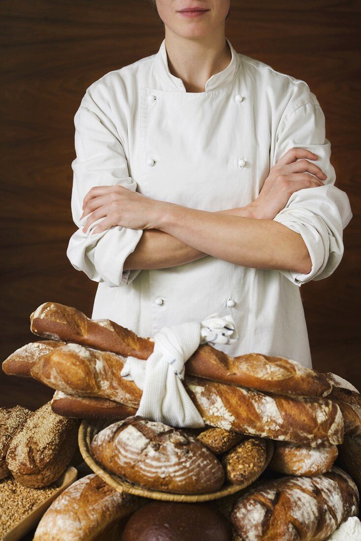 Baker with various rustic loaves of bread
