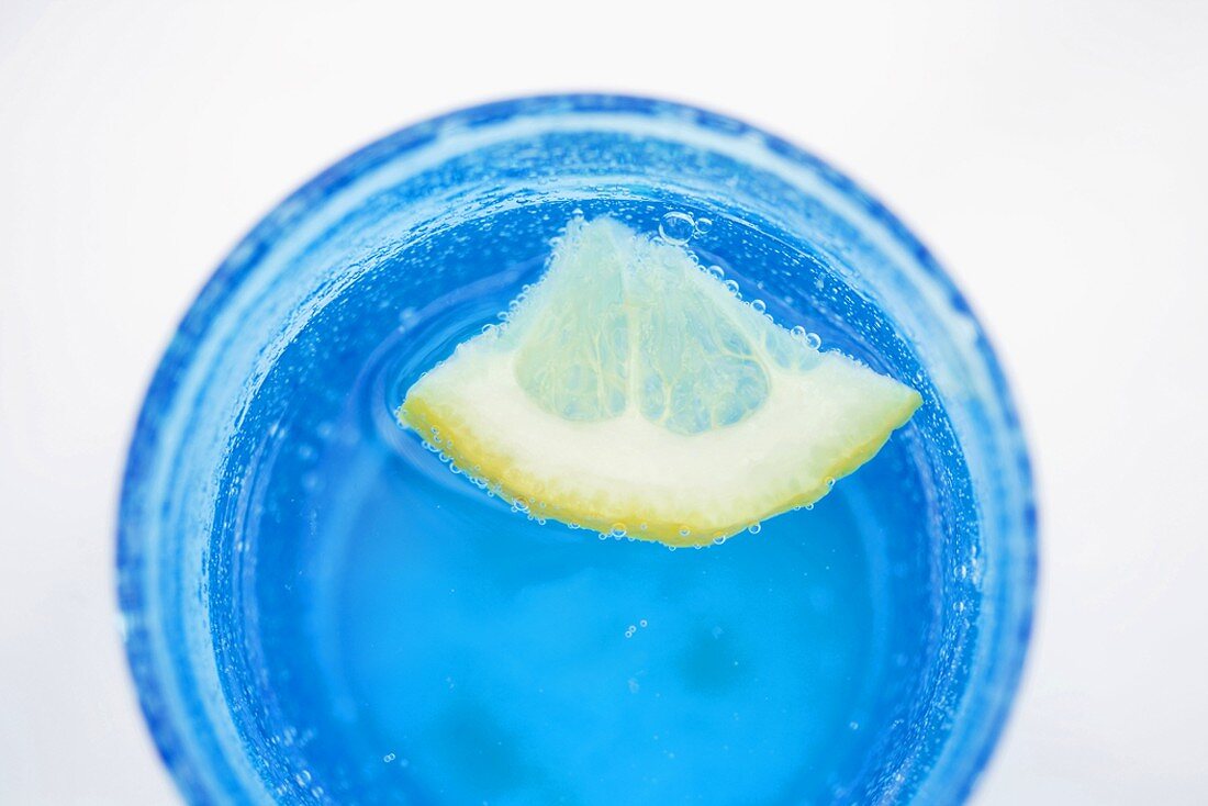 Wasser mit Zitronenschnitz in blauem Glas
