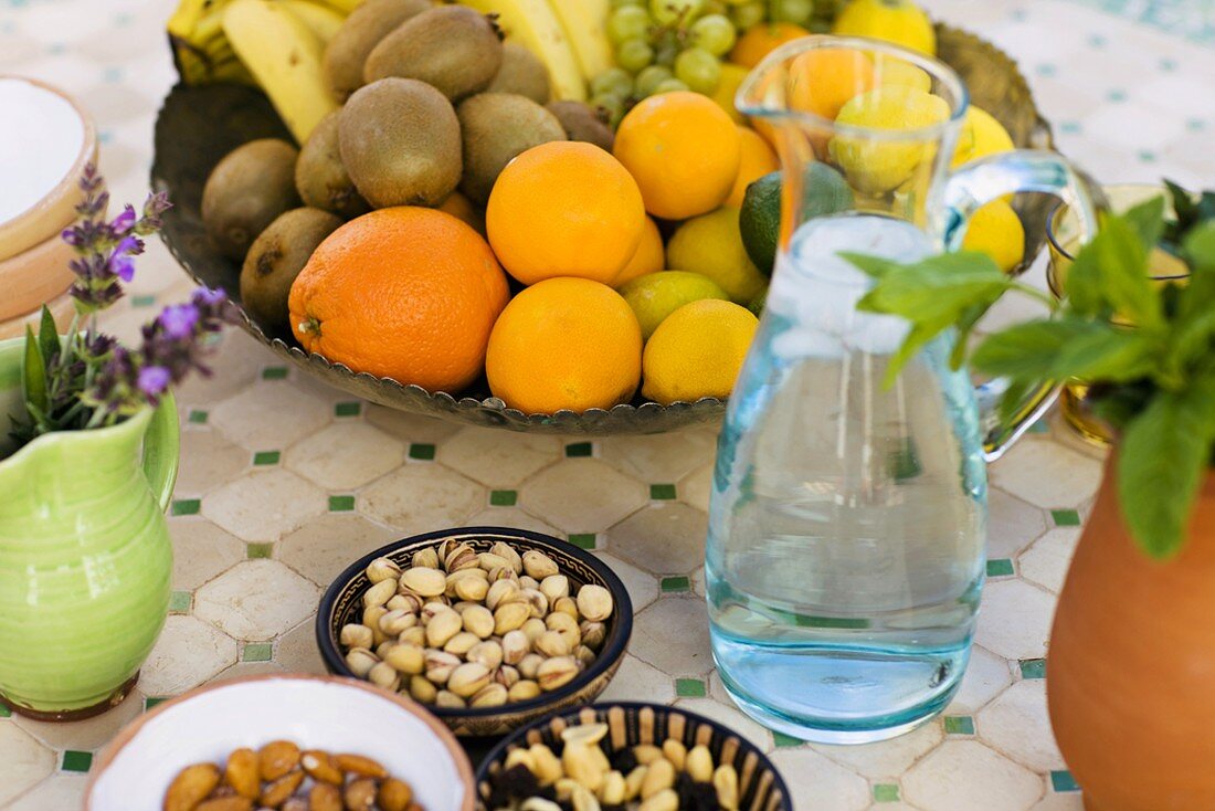 Fruit bowl, nuts and jug of water on table