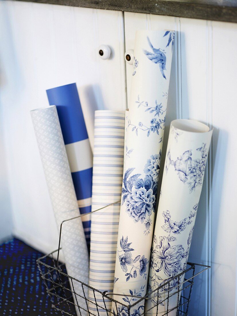 Rolls of different wallpaper in front of cupboard