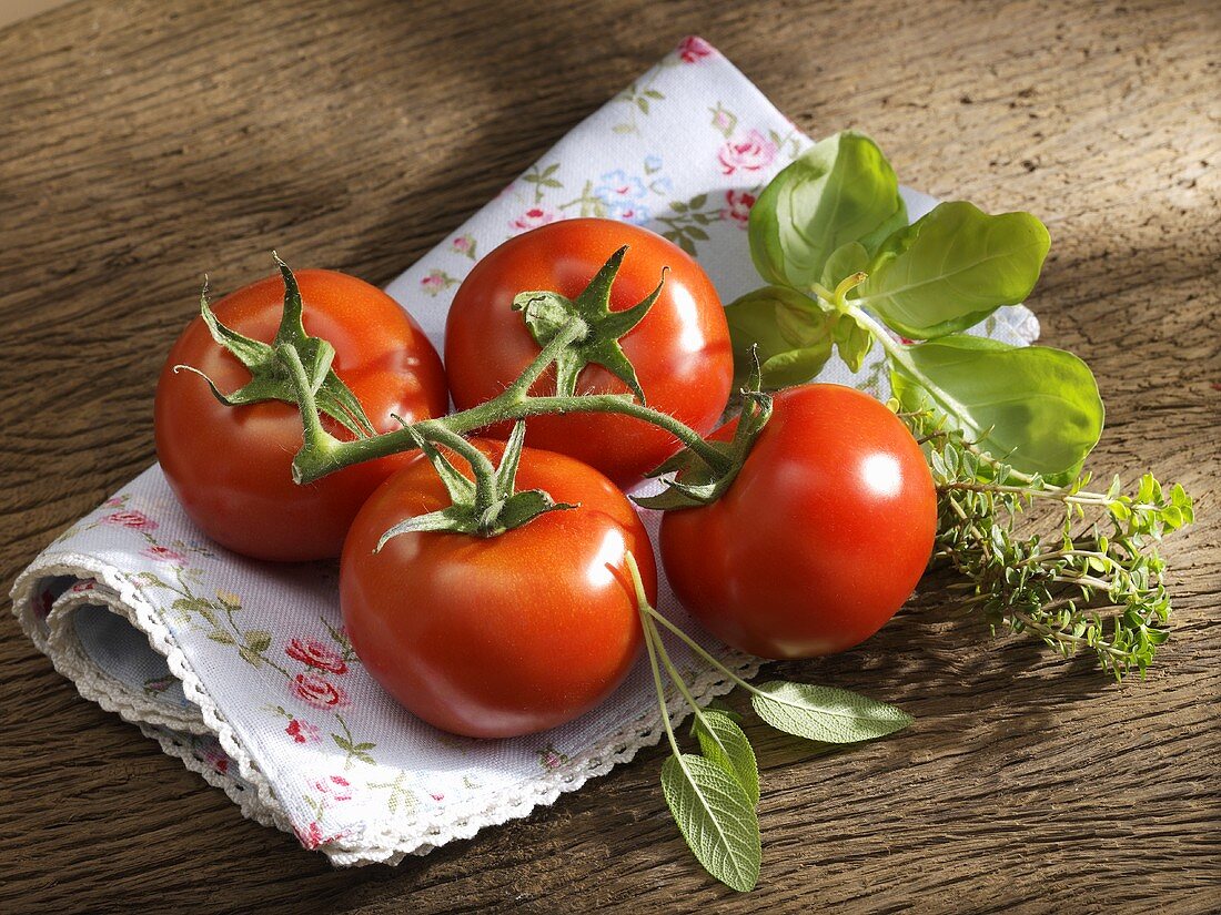 Frische Tomaten und Kräuter auf geblümtem Tuch