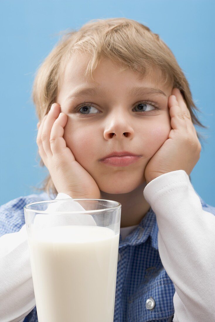 Little boy sitting in front of glass of milk