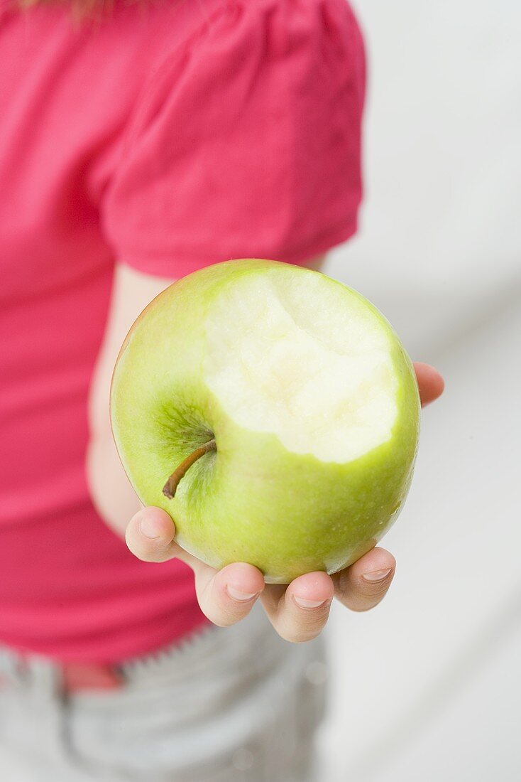 Kind hält angebissenen Apfel