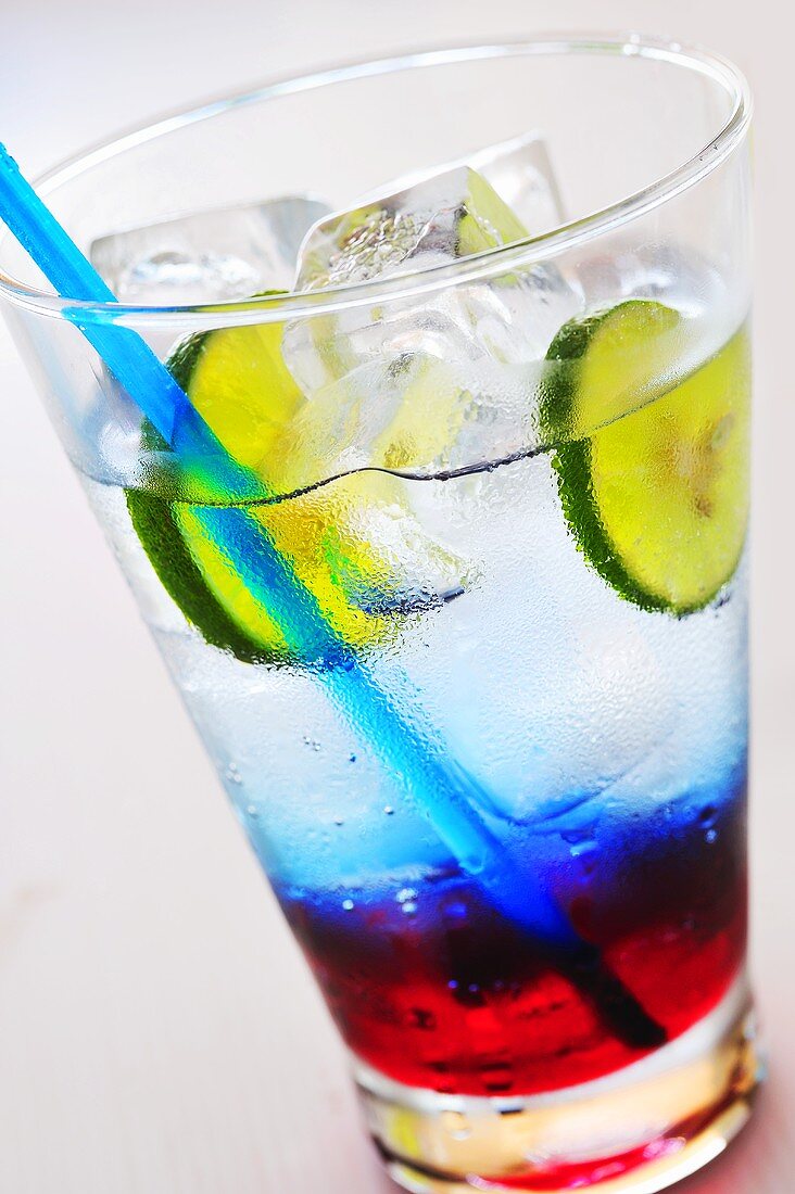 Coloured soft drink with ice cubes and lime slices
