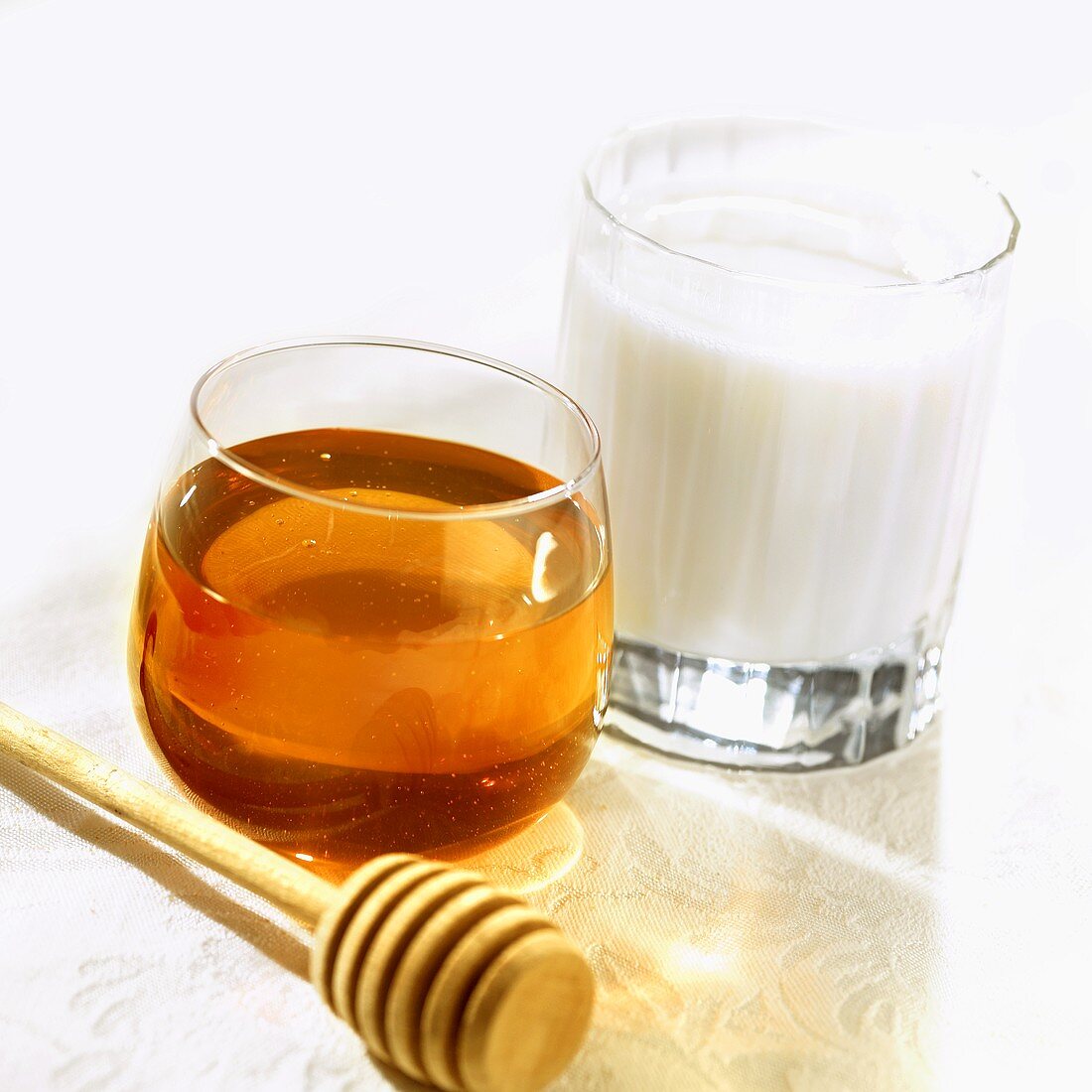 Glass of honey, honey dipper and glass of milk