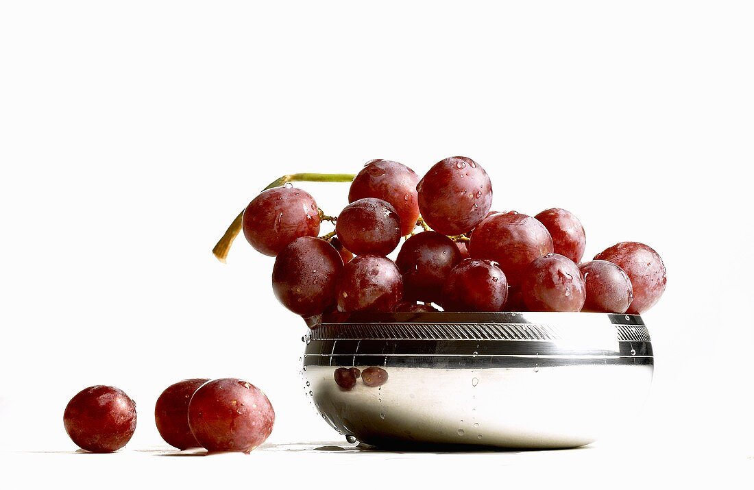 Fresh red grapes in and beside silver bowl