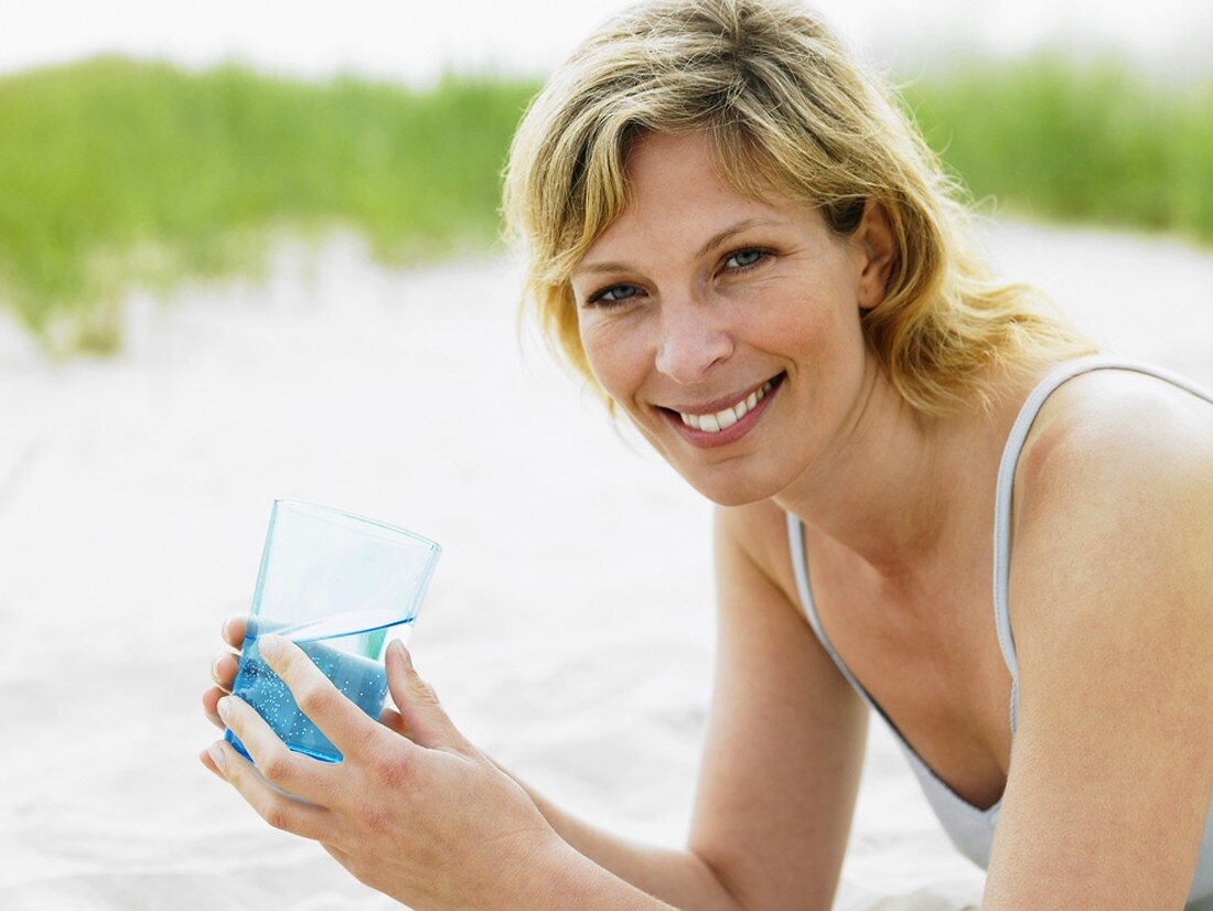 Frau mit Glas Wasser am Strand