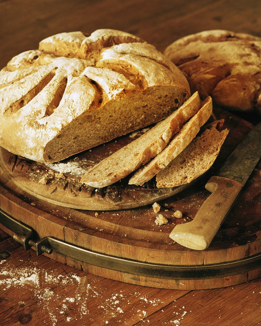 Crusty bread, partly sliced, on breadboard